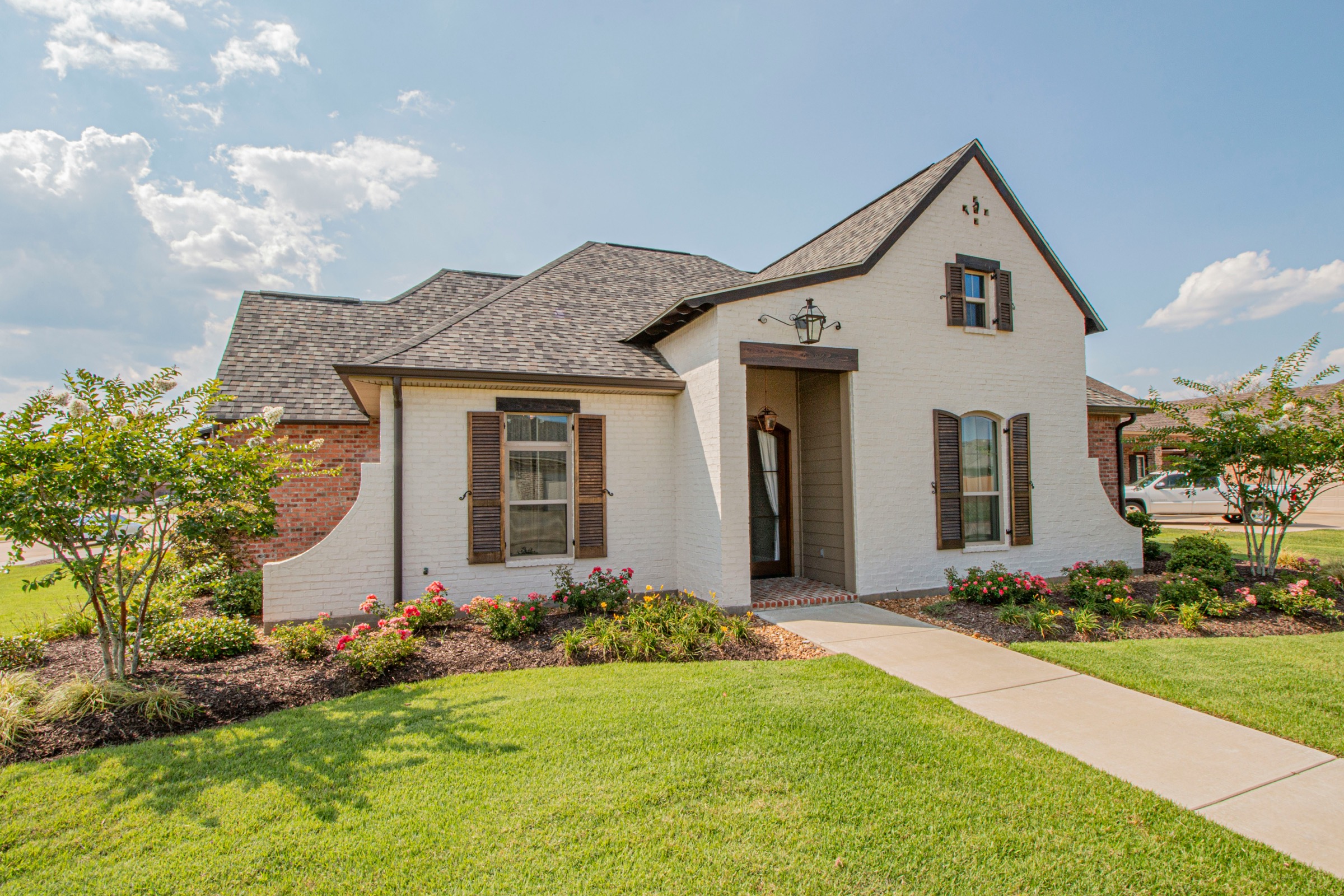 Front yard landscaping with a lawn, walkway, and planted beds