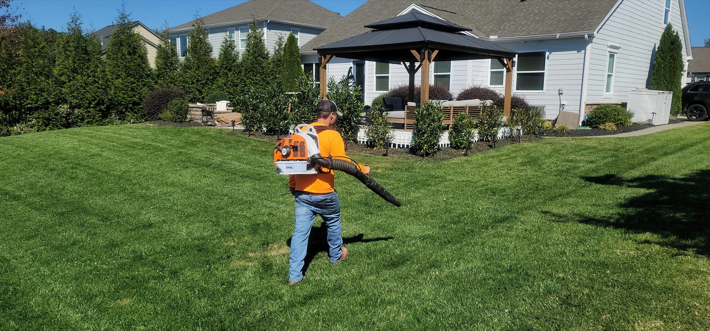 Lawn care worker blowing clippings across a maintained backyard
